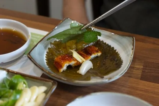 젓가락으로 장아찌 잎 위에 장어구이 한 점을 올리는 모습