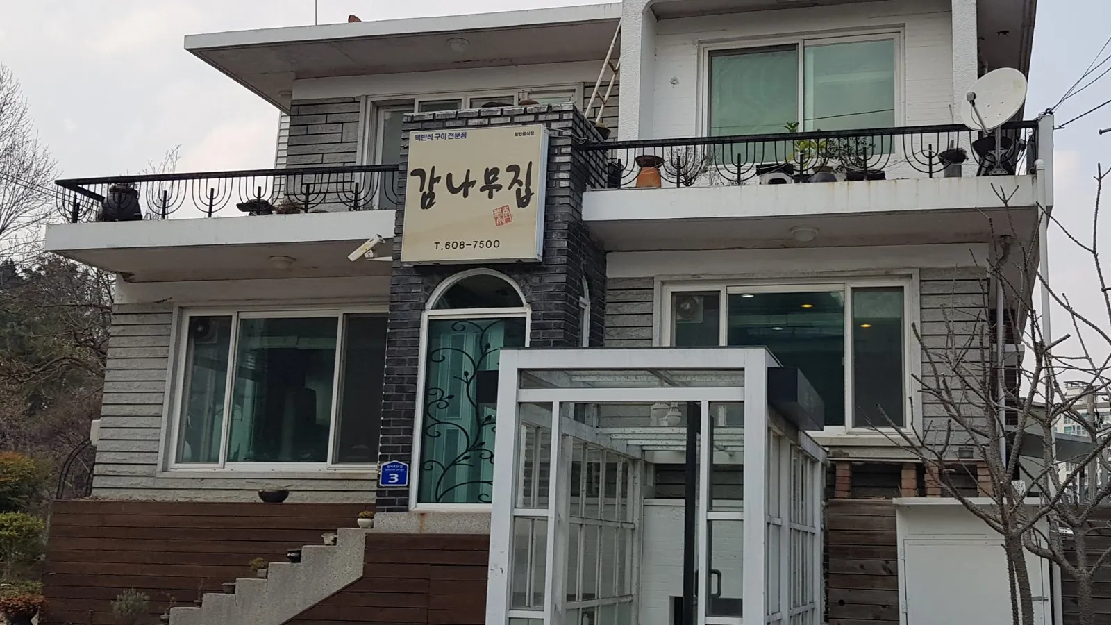 감나무집 건물 바깥 — 2층 흰 집과 검은 벽돌 기둥의 간판