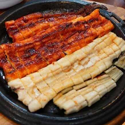 무쇠판에 나란히 담은 양념구이와 소금구이, 뒤로 장어탕
